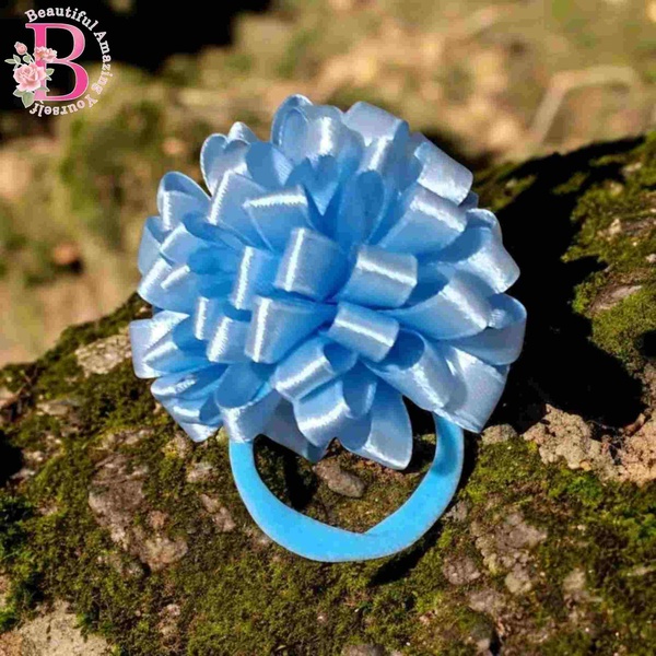 Light blue satin ribbon pom pom hair tie displayed on moss rock, perfect for school hairstyles and cute ponytails.