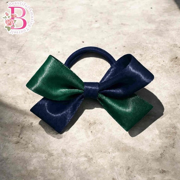 Navy blue and emerald green layered hair bow on a navy elastic band, styled with glossy ribbon loops on a neutral background.