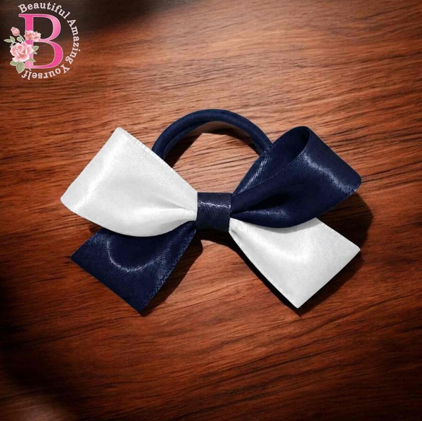 Navy blue and white satin hair bow on a matching elastic band, displayed on a wooden background with elegant glossy ribbon detail.