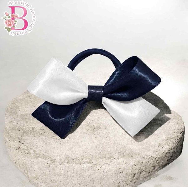 Navy blue and white boutique hair bow on elastic band, displayed on stone surface with elegant satin ribbon loops and classic style.