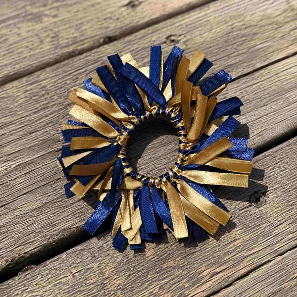 Navy and gold ribbon scrunchie hair tie on rustic wood deck with layered satin strips and textured elastic center band.