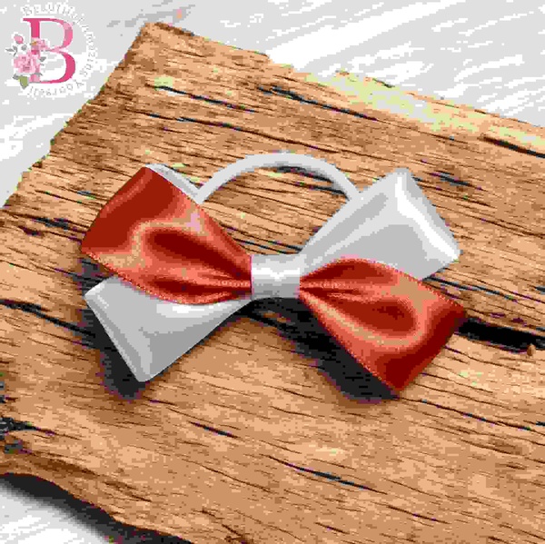 White and coral satin school hair bow on rustic wood background with soft loops and tails, ideal for girls ponytails or buns.