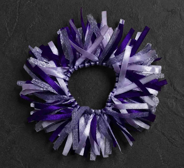 Purple and silver ribbon scrunchie hair tie on a dark stone background with layered satin and glitter strands for styling.