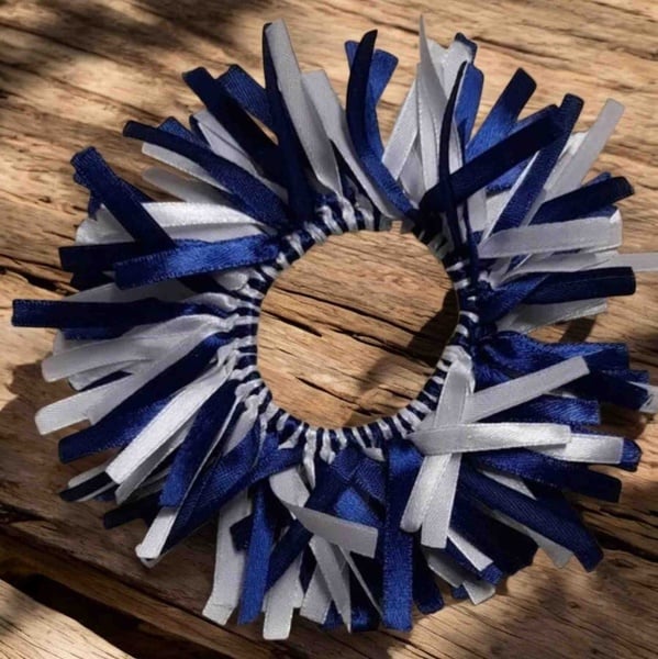 Navy blue and white ribbon scrunchie hair tie on rustic wood background with soft shadows and textured satin ribbon detail.
