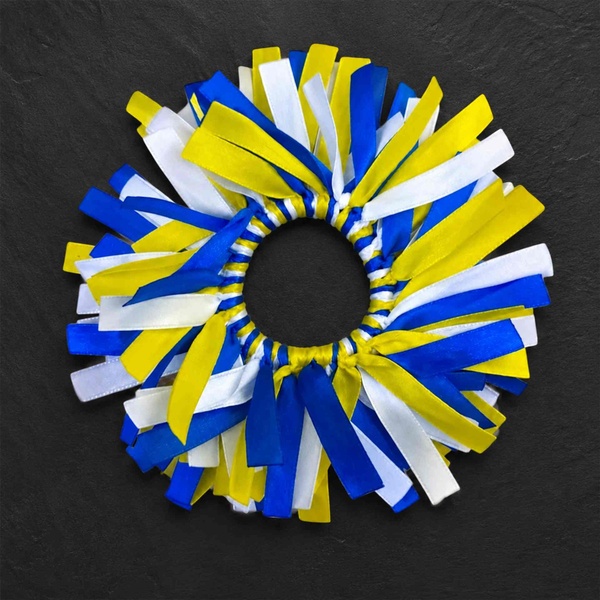 Blue, yellow and white ribbon hair scrunchie with layered satin strips on a dark textured background for sporty hairstyles.