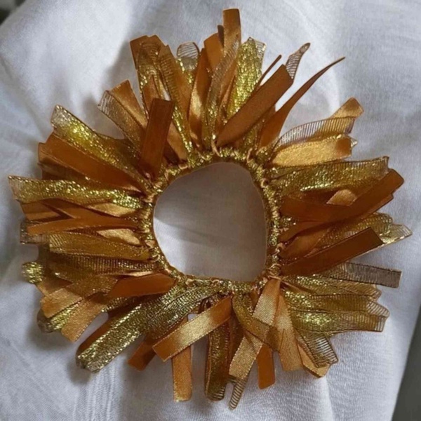 Gold ribbon hair scrunchie with layered metallic strands on a soft white background, elegant festive hair accessory design.