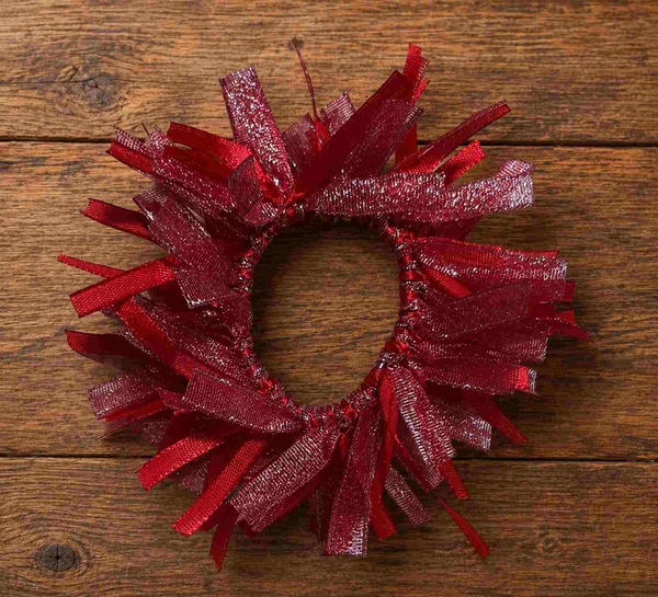 Red glitter ribbon hair scrunchie on rustic wooden background, handcrafted textured accessory with festive elegant style.