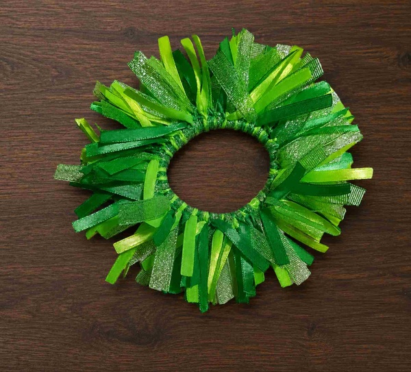 Lime glitter green ribbon scrunchie hair tie on dark imbuia wood tabletop with layered textured ribbons and sparkle detail.