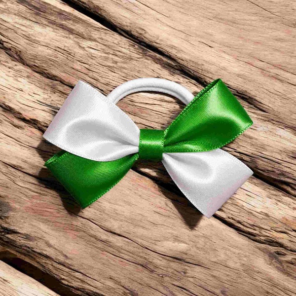 Green and white satin ribbon hair bow on a white elastic band, displayed on rustic driftwood, featuring a classic two-tone design.