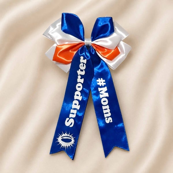 Blue, white and orange satin supporter bow on a soft neutral fabric background with #Moms text and ribbon tails.