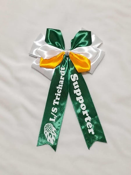 Green, white and gold satin supporter bow with custom LS Trichardt Supporter text and graphic on a soft neutral background.