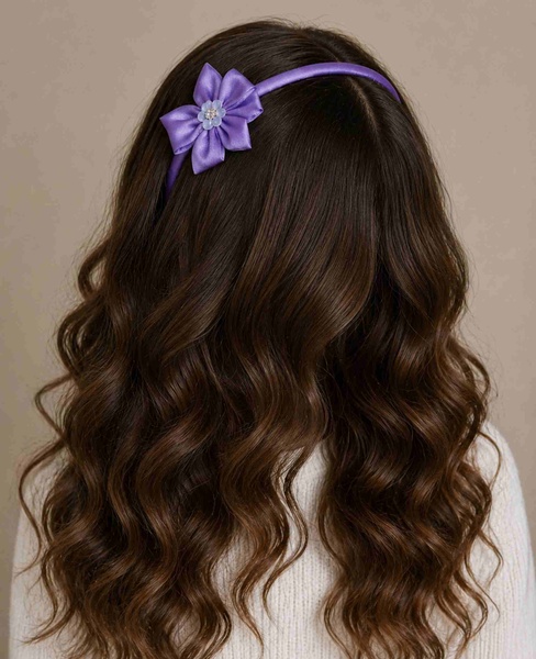 Purple satin flower headband showcased from a rear top-angle view on flowing brunette hair, emphasizing the handcrafted floral detail.