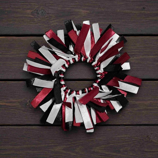 Handmade ribbon hair scrunchie featuring maroon, black, and white ribbons arranged in a full layered design on a dark wood surface.