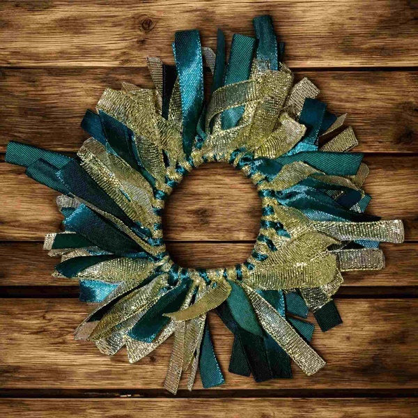 Handmade green and gold ribbon scrunchie displayed flat on a rustic wooden tabletop, featuring layered satin and metallic ribbons.