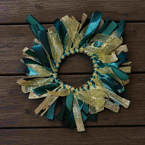 Elegant green and gold ribbon scrunchie showcased on a dark wooden surface, featuring layered satin and metallic ribbons.