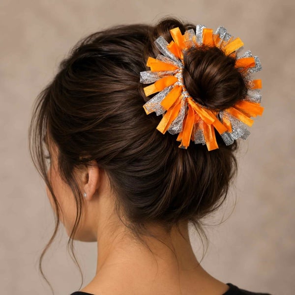 Brunette girl viewed from behind left wearing an orange and silver ribbon scrunchie in a bun against a soft neutral background.