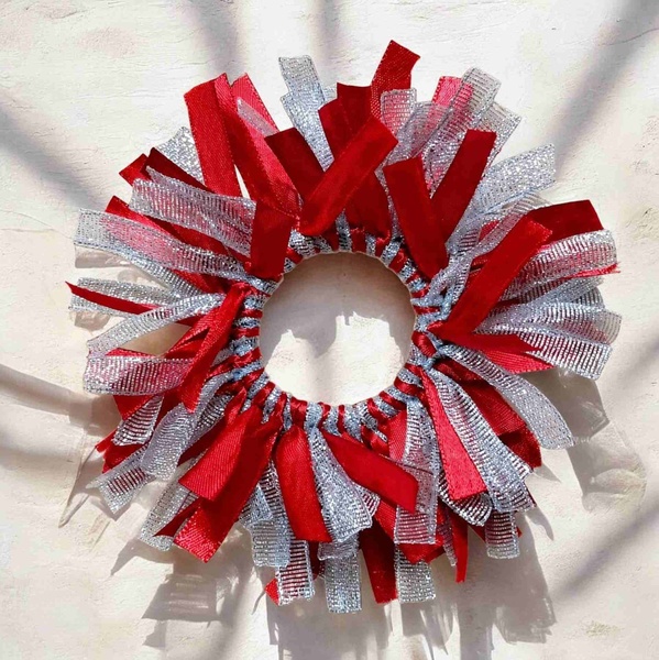 Red and silver ribbon scrunchie with layered textured strands, photographed on a soft neutral background with natural shadows.