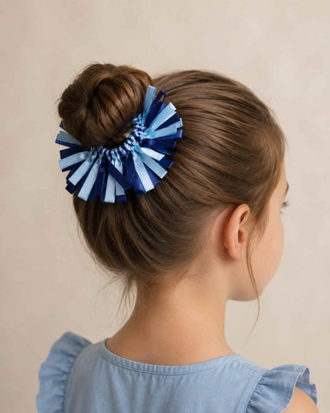 Girl viewed from the back right wearing a navy and light blue ribbon scrunchie around a neat hair bun on a soft neutral background.