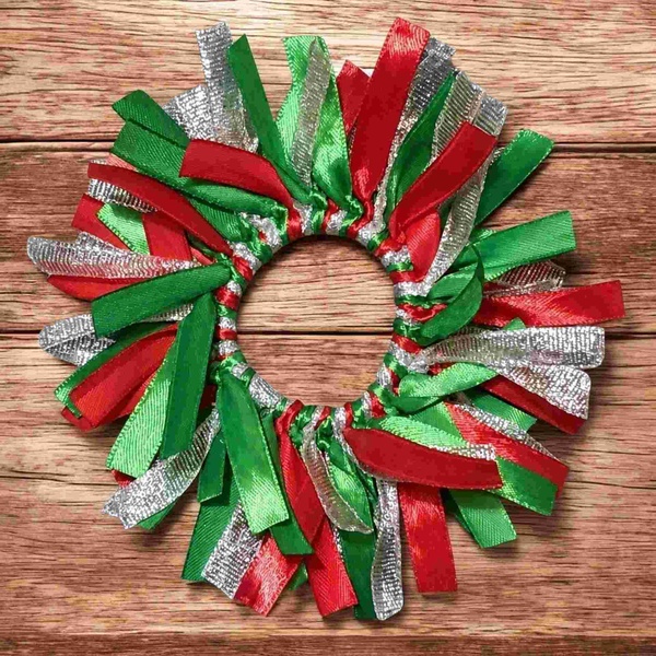 Red, green, and silver ribbon scrunchie displayed on a rustic wooden background, featuring layered satin and metallic ribbons.