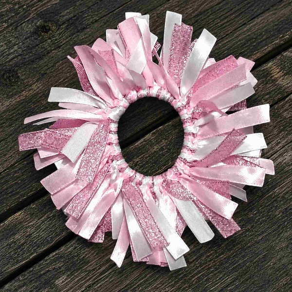 Pink and white ribbon scrunchie featuring satin and glitter ribbon strands, arranged in a full circle on a rustic wooden surface.