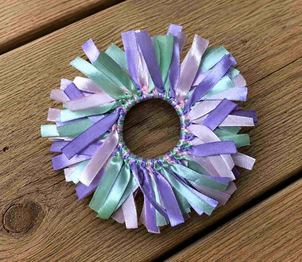 Handmade ribbon scrunchie featuring pastel lavender, lilac, mint, and aqua satin ribbons arranged around an elastic hair tie.
