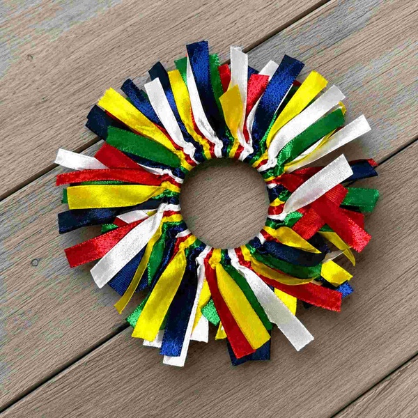 Colorful South African ribbon scrunchie with red, blue, green, yellow and white satin ribbons displayed on a light wood deck.