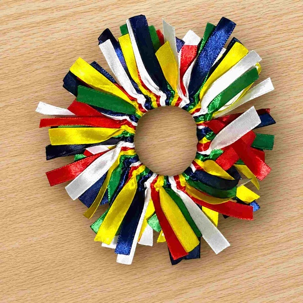 South African ribbon scrunchie featuring red, blue, green, yellow and white satin ribbons arranged in a circle on light wood.