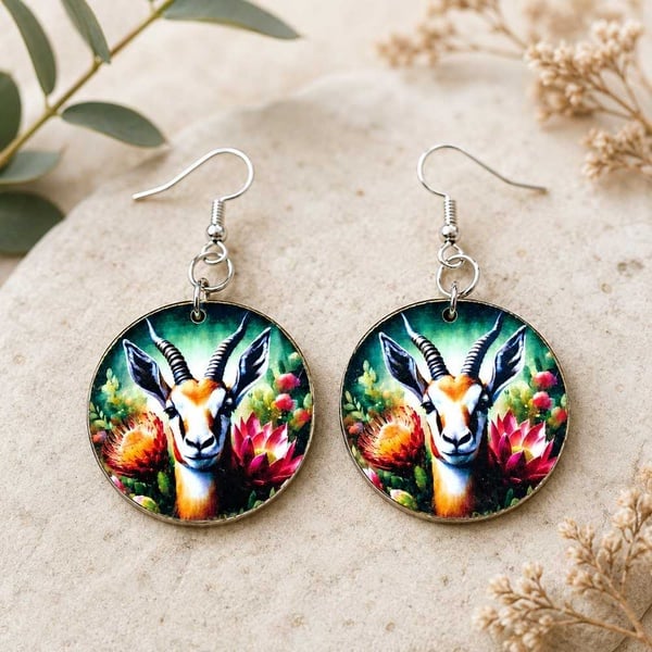 Handmade South African springbok and protea round dangle earrings with hypoallergenic hooks on a natural stone with foliage decor.