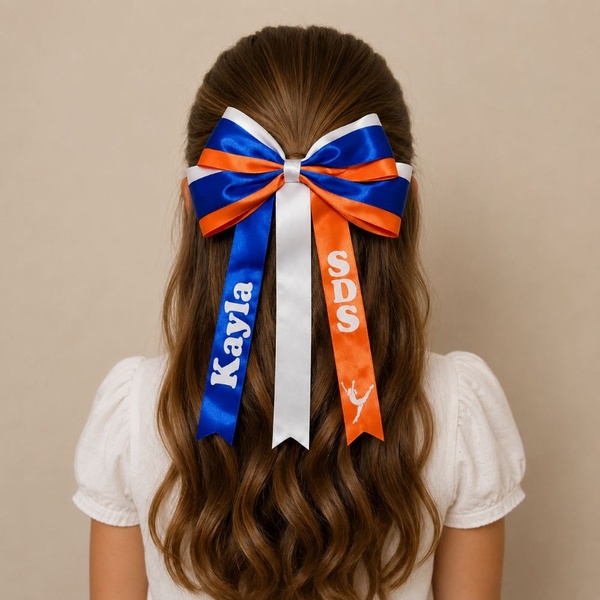 Girl viewed from behind wearing a personalised SDS dance hair bow in blue, orange and white satin ribbons with custom name print.
