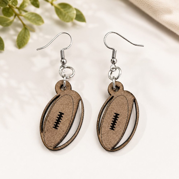 Wooden rugby ball dangle earrings with silver hooks on a soft neutral background, lightweight handmade sports-inspired jewelry.