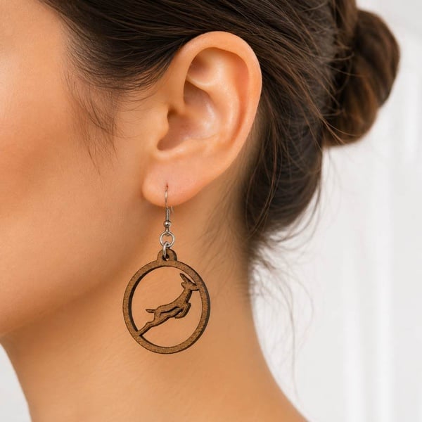 Woman wearing handmade Springbok rugby wooden hoop earring with leaping springbok design, lightweight South African fan jewellery.