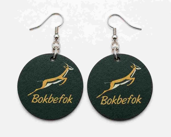 Round green Bokbefok-inspired dangle earrings with silver hooks, featuring a leaping antelope graphic and gold lettering on white background.