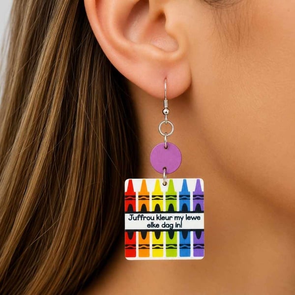 Close-up of handmade colourful MDF teacher crayon dangle earrings worn in a woman's ear, lightweight Afrikaans appreciation gift.