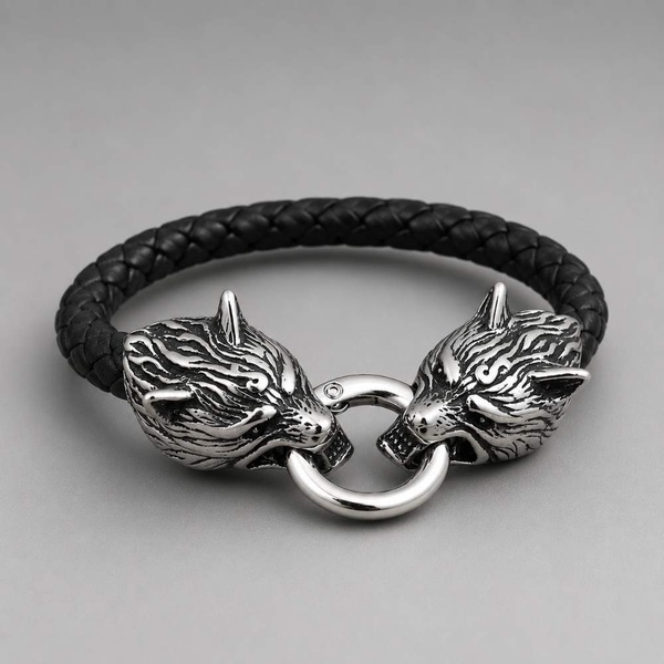 Black braided leather wolf head bracelet on a smooth neutral grey background with soft studio lighting highlighting the silver clasp.