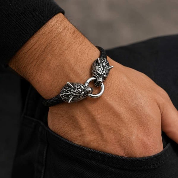 Men's black braided leather bracelet with detailed stainless steel wolf head clasp, worn on wrist, close-up against a neutral background.