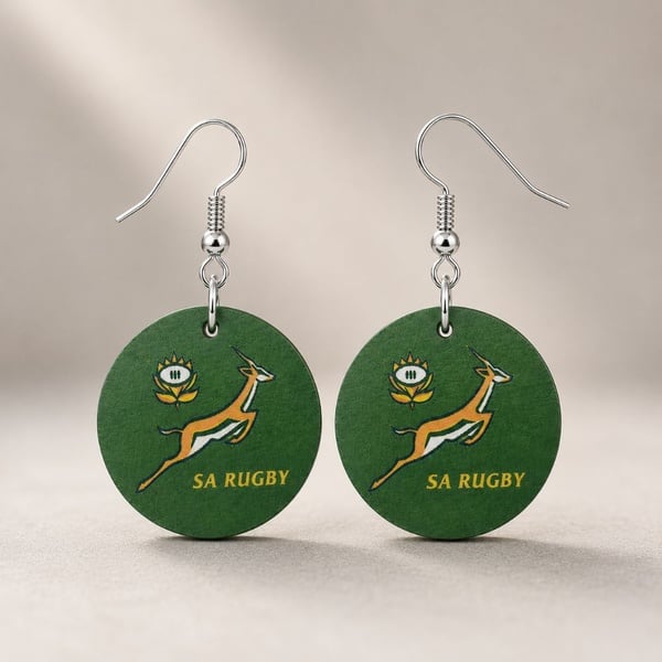 Green round SA Rugby inspired dangle earrings with silver hooks, featuring a leaping antelope design on a soft neutral background.