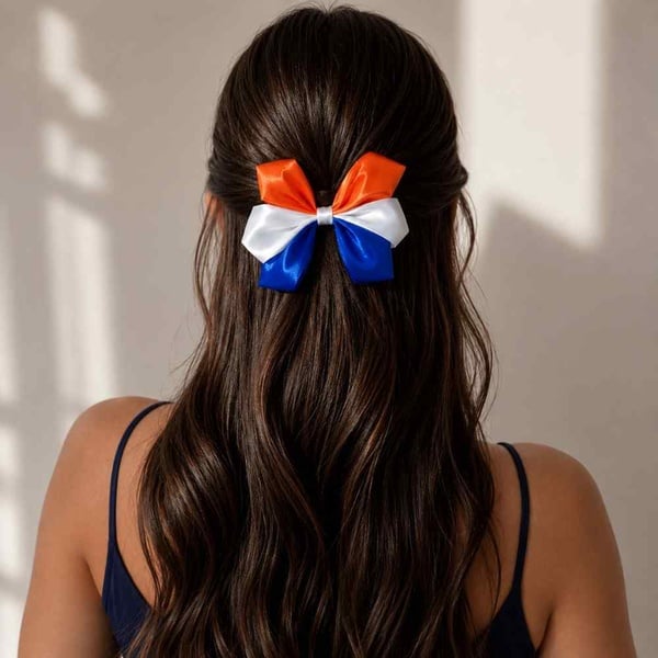 Orange, white and blue handmade satin hair bow on a girl's ponytail viewed from behind with a neutral background for online shopping.
